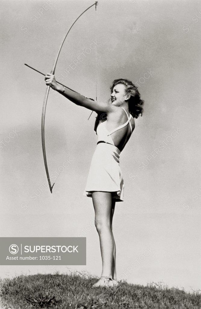 Stock Photo: 1035-121 Low angle view of a young woman aiming with a bow and arrow