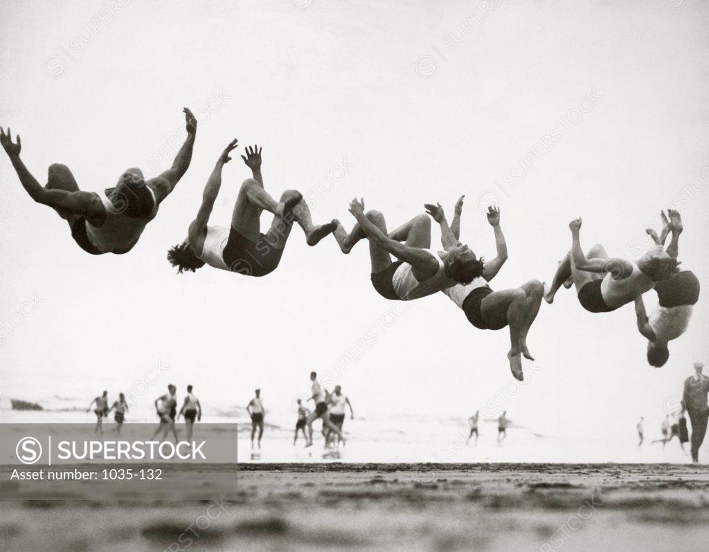Stock Photo: 1035-132 Group of teenage boys performing back flip on the beach