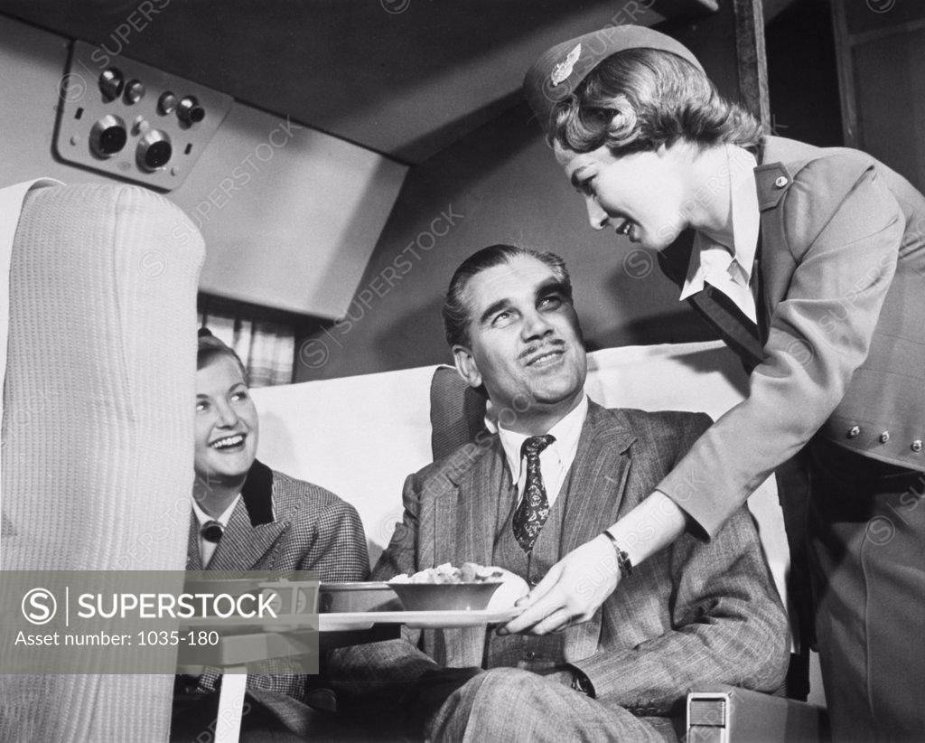 Stock Photo: 1035-180 Airplane stewardess serving meals to passengers in an airplane