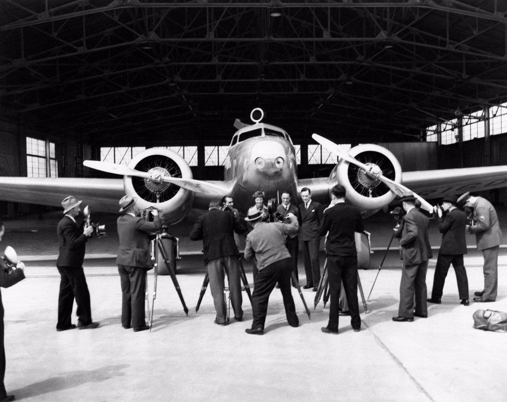 United States:  1937 Photographers taking photos of (L-R), Paul Mantz, Amelia Earhart, Harry Manning, and Fred Noonan, all posed in front of Earhart's Lockheed Electra 10E