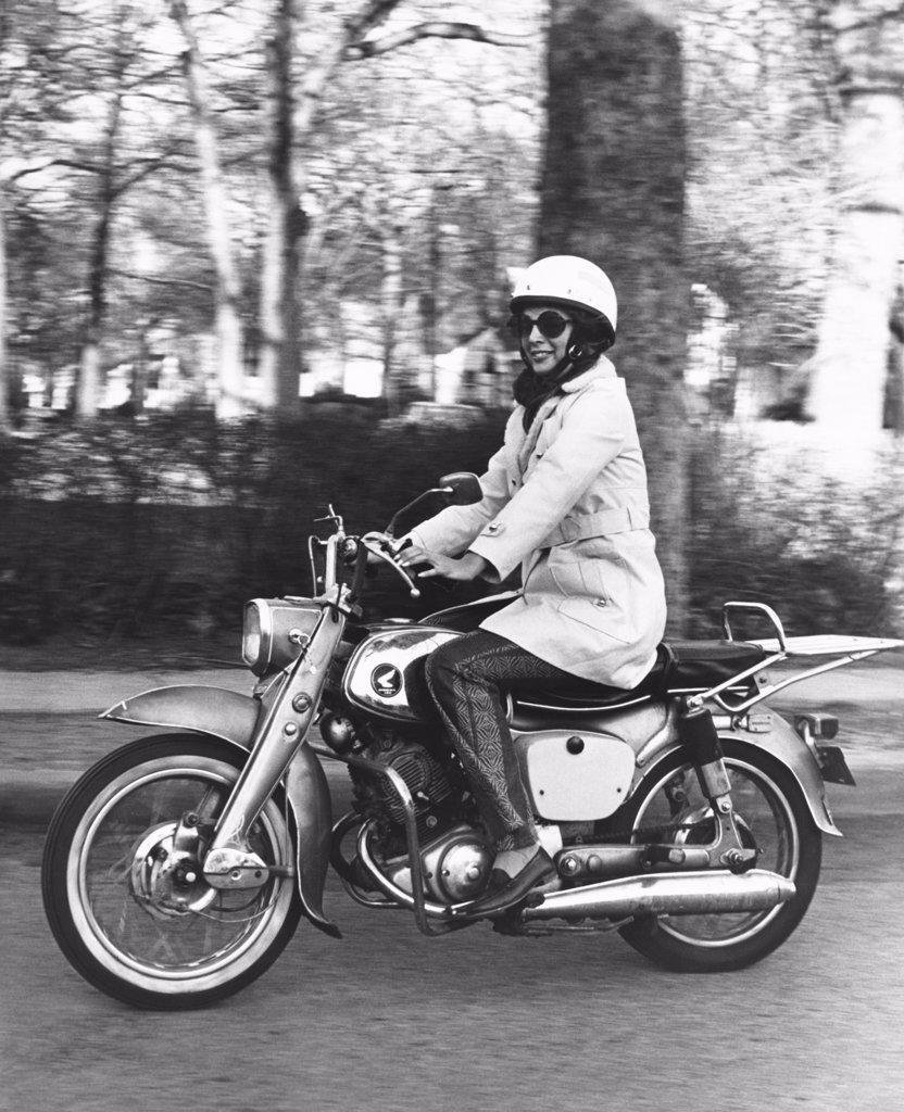 United States:   c. 1961 A woman riding her Honda 160 motorcycle.