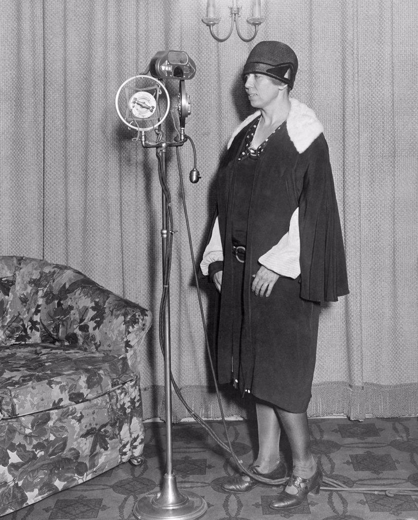 New York, New York:  c. 1926 A woman stands in front of the WHN Radio microphone.