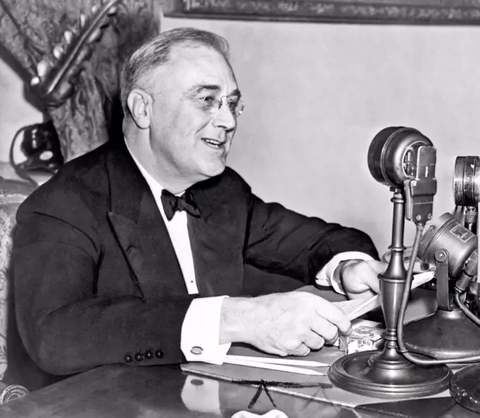 Washington, D.C.:  1937. President Franklin D. Roosevelt, seated behind microphone, during one of his fireside chats.
