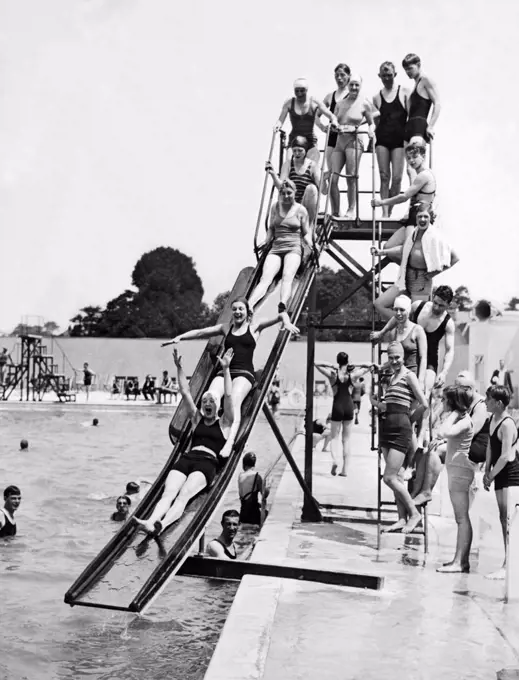 London, England:  June 5, 1933 Swimmers sliding down the water chute at the opening of the new Lagoon Swimming Pool at Orpington Garden Village.