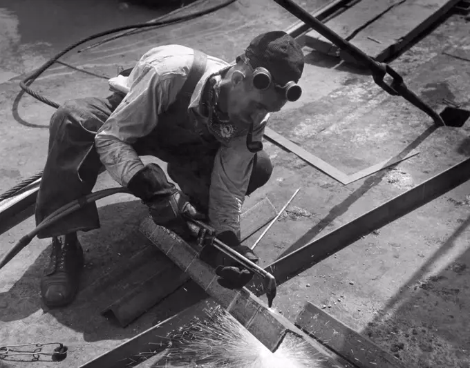 United States:  c. 1938 A workman using an oxy acetylene torch to cut steel angle iron.
