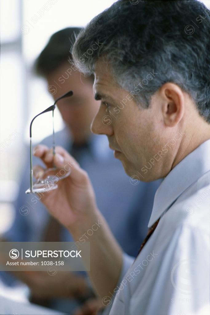 Stock Photo: 1038-158 Side profile of a businessman holding eyeglasses