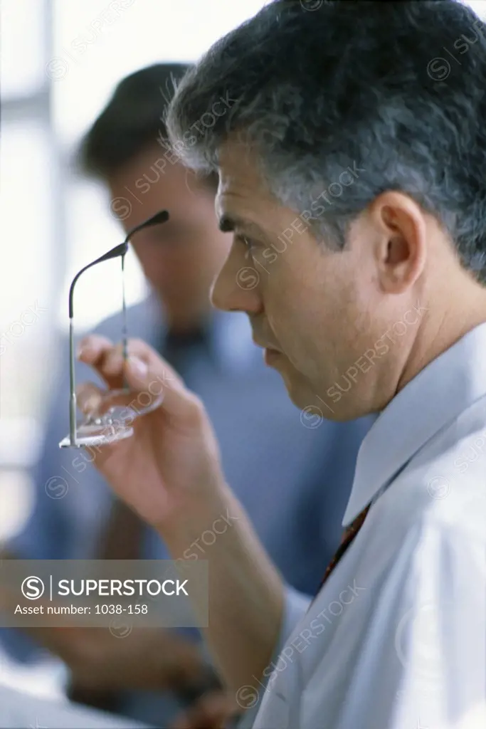 Side profile of a businessman holding eyeglasses