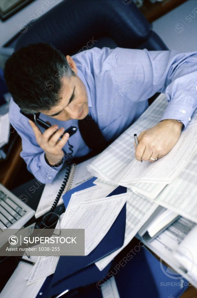 Stock Photo: 1038-255 High angle view of a businessman writing and talking on the telephone