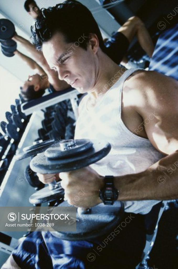 Stock Photo: 1038-289 Young man exercising with dumbbells
