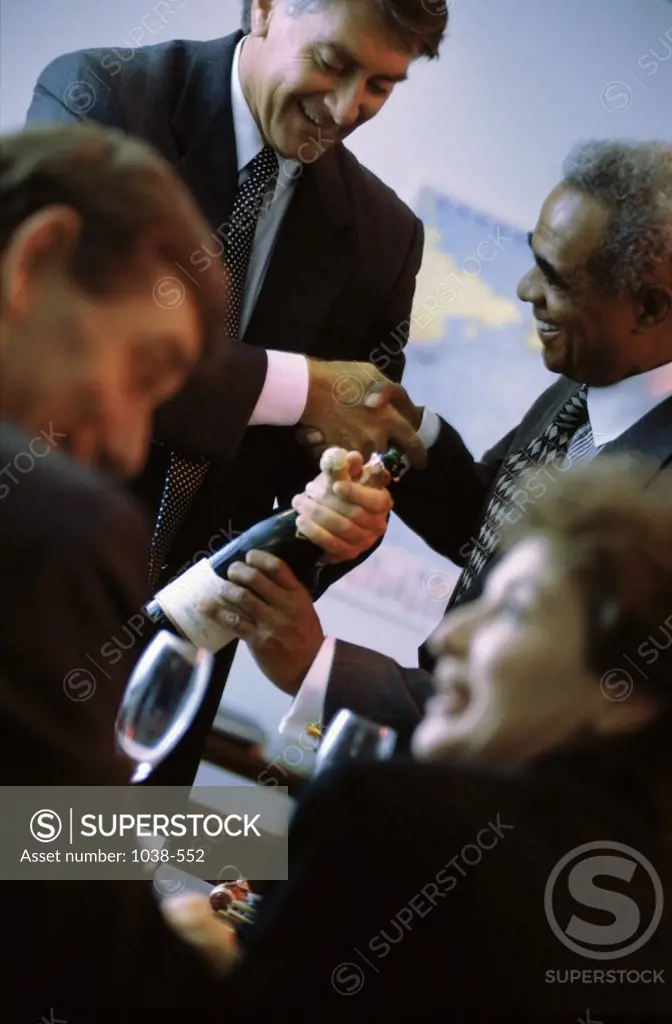 Business executives in an office with a bottle of champagne
