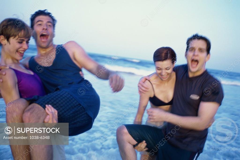 Stock Photo: 1038-634B Two young women carrying two young men on the beach