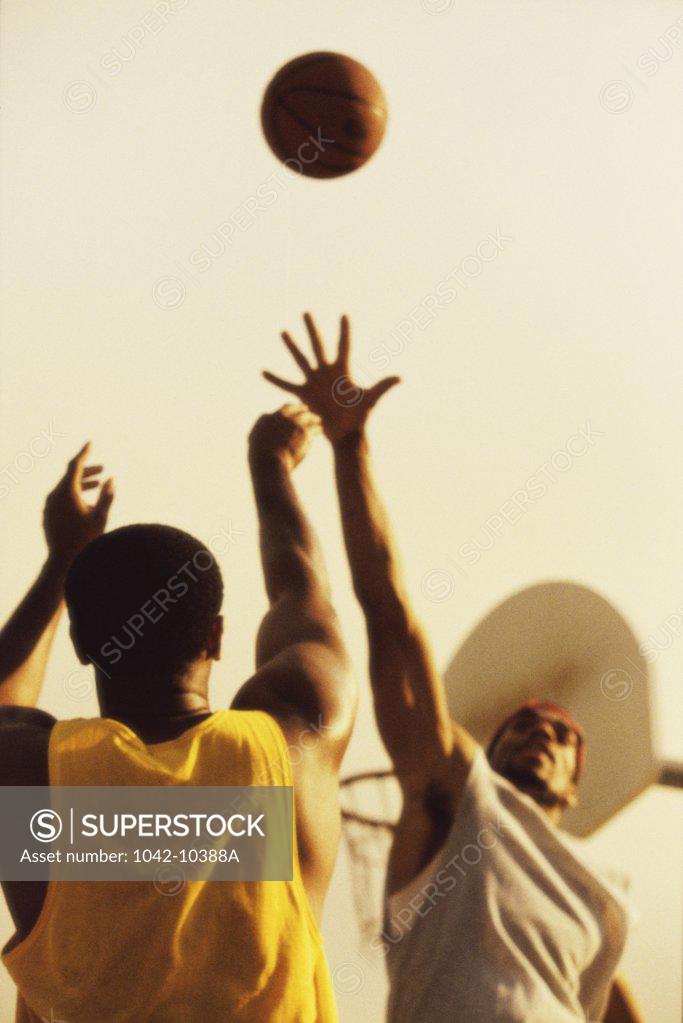 Stock Photo: 1042-10388A Low angle view of two young men playing basketball