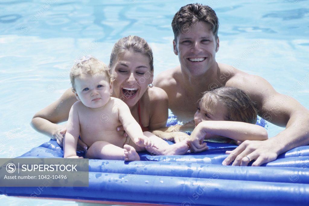 Stock Photo: 1042-10496 Portrait of a young couple on a pool raft with their two daughters