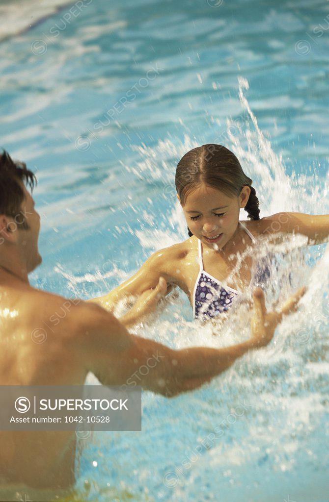 Stock Photo: 1042-10528 Father and his daughter playing in a swimming pool