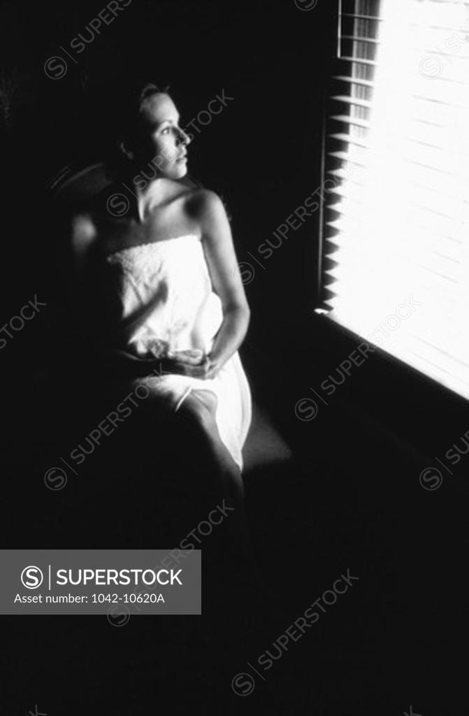 Stock Photo: 1042-10620A Young woman wrapped in a towel looking out of a window
