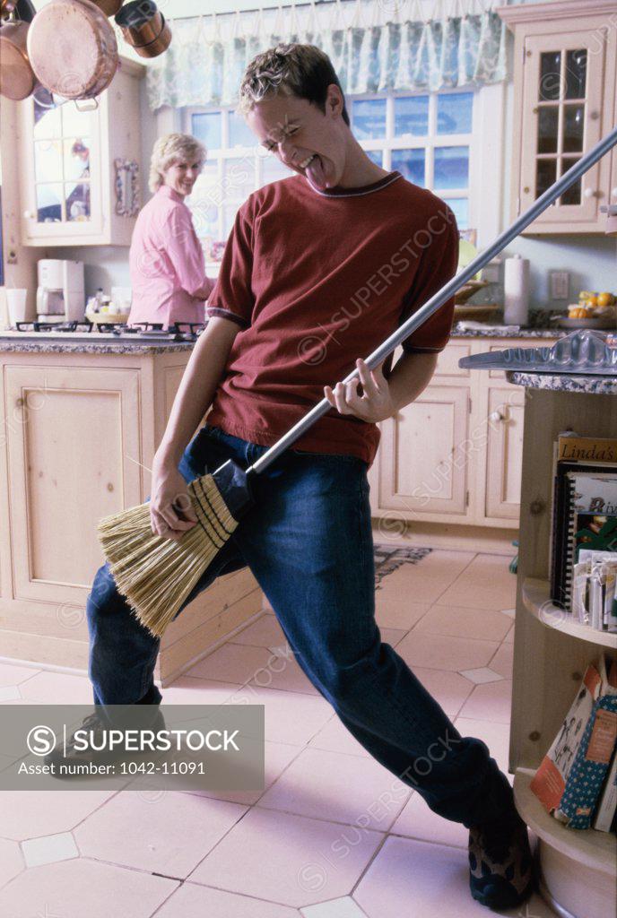 Stock Photo: 1042-11091 Young man pretending to play a guitar with a broom