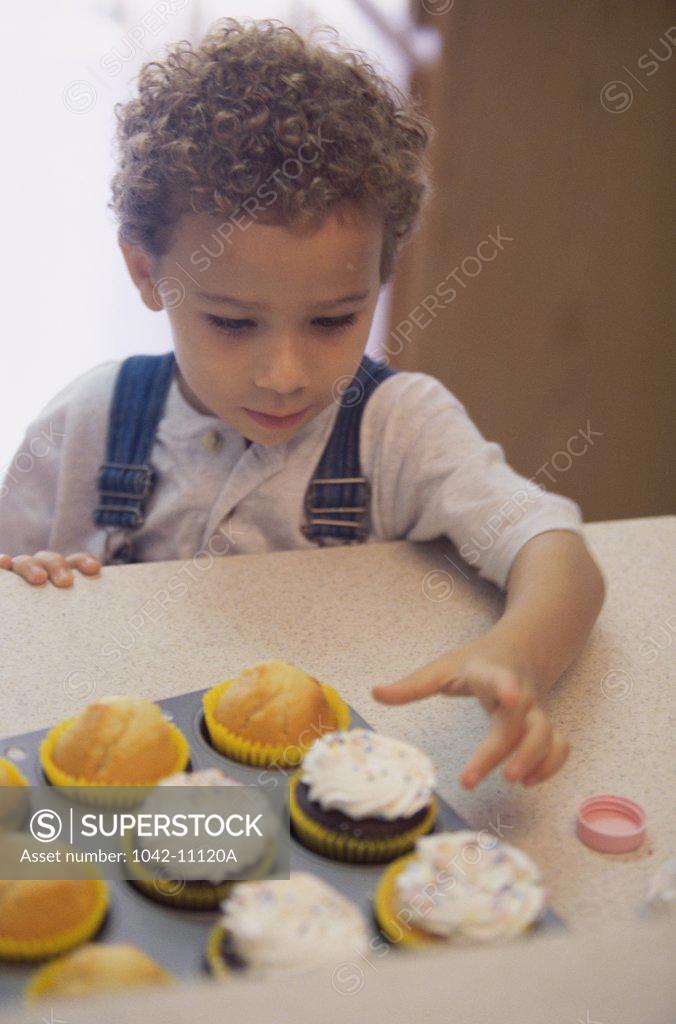 Stock Photo: 1042-11120A Boy taking a cupcake from a tray