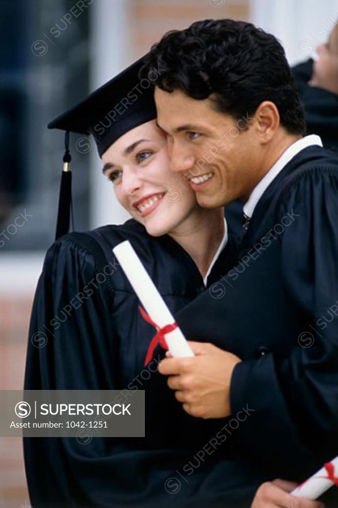 Stock Photo: 1042-1251 Young male graduate hugging a young female graduate