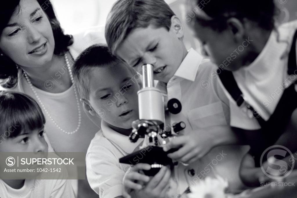 Stock Photo: 1042-1542 Children looking into a microscope with their teacher
