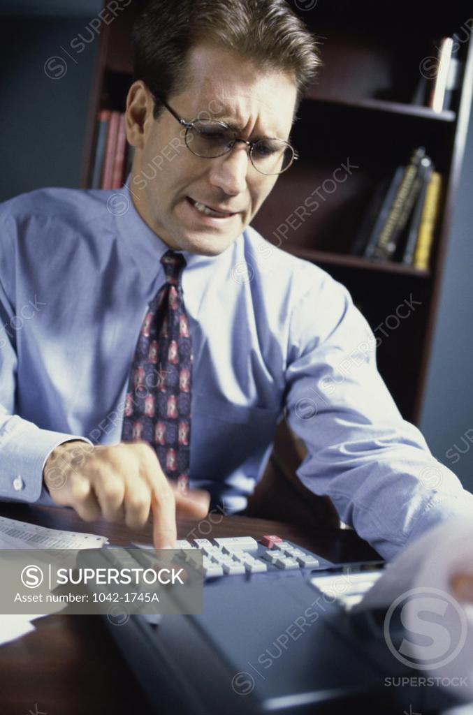 Stock Photo: 1042-1745A Businessman using an adding machine