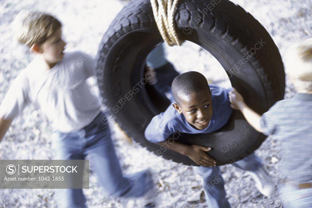 Stock Photo: 1042-1855 Two boys playing on a tire swing