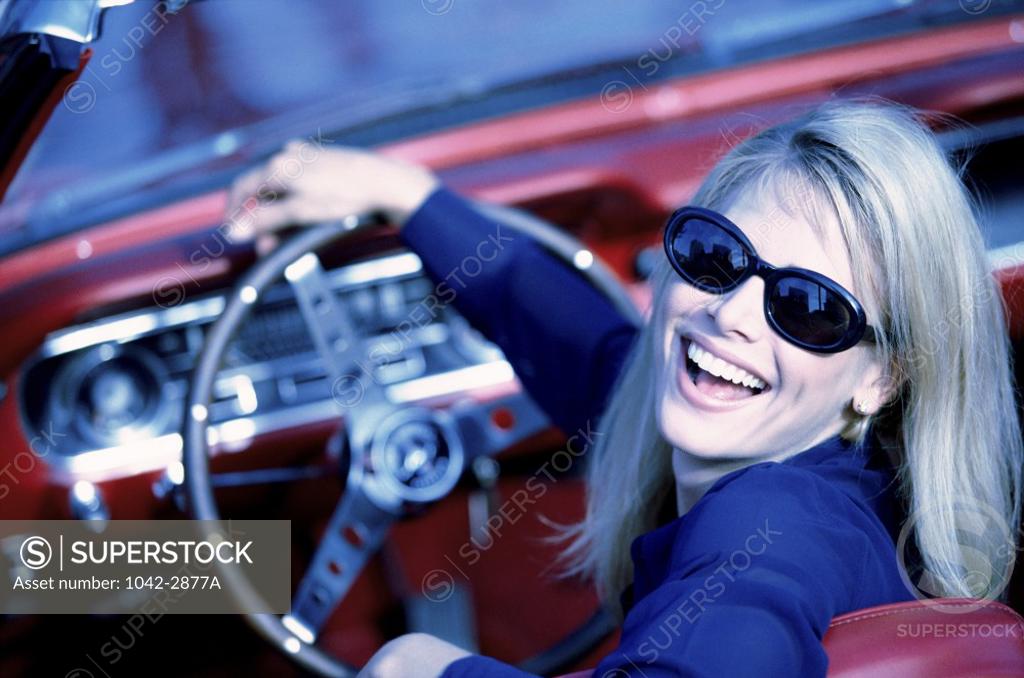 Stock Photo: 1042-2877A Portrait of a young woman sitting in car holding a steering wheel
