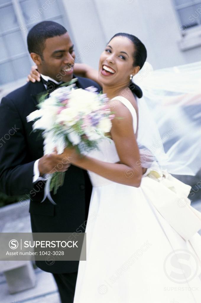 Stock Photo: 1042-3028 Newlywed couple holding a bouquet of flowers