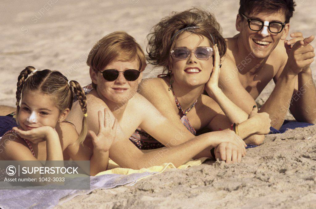 Stock Photo: 1042-3033 Portrait of a young couple lying on the beach with their son and daughter