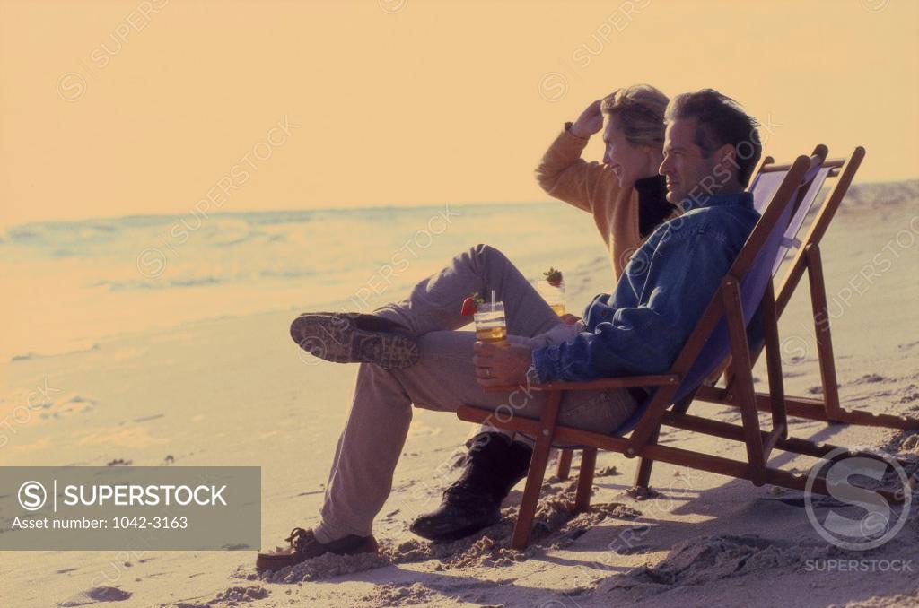 Stock Photo: 1042-3163 Mid adult couple sitting in lounge chairs on the beach