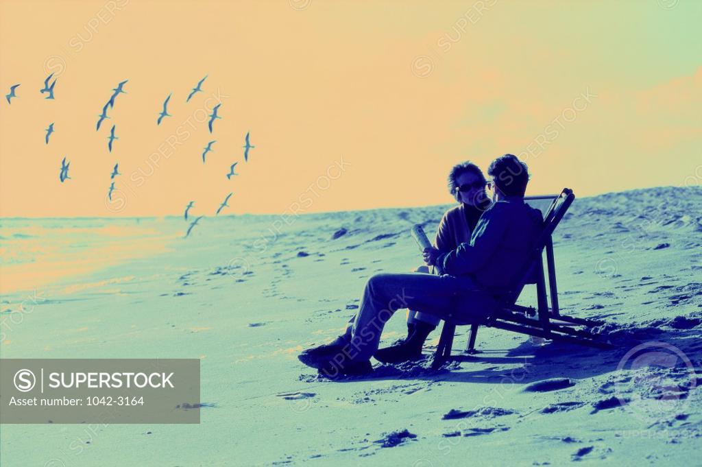 Stock Photo: 1042-3164 Mid adult couple sitting in lounge chairs on the beach