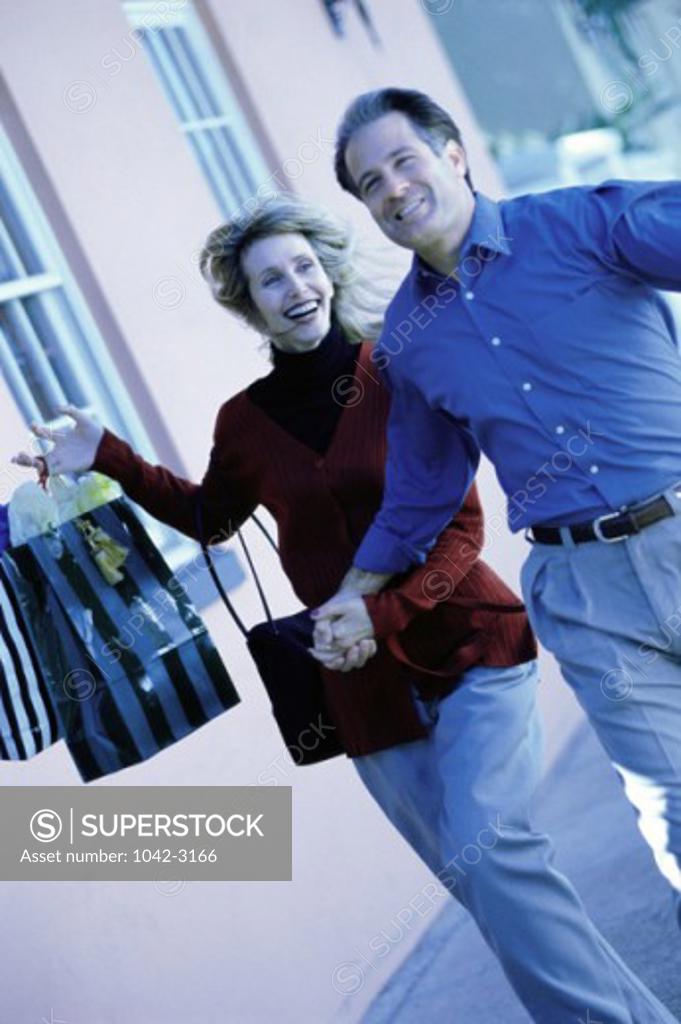 Stock Photo: 1042-3166 Mature couple running with shopping bags