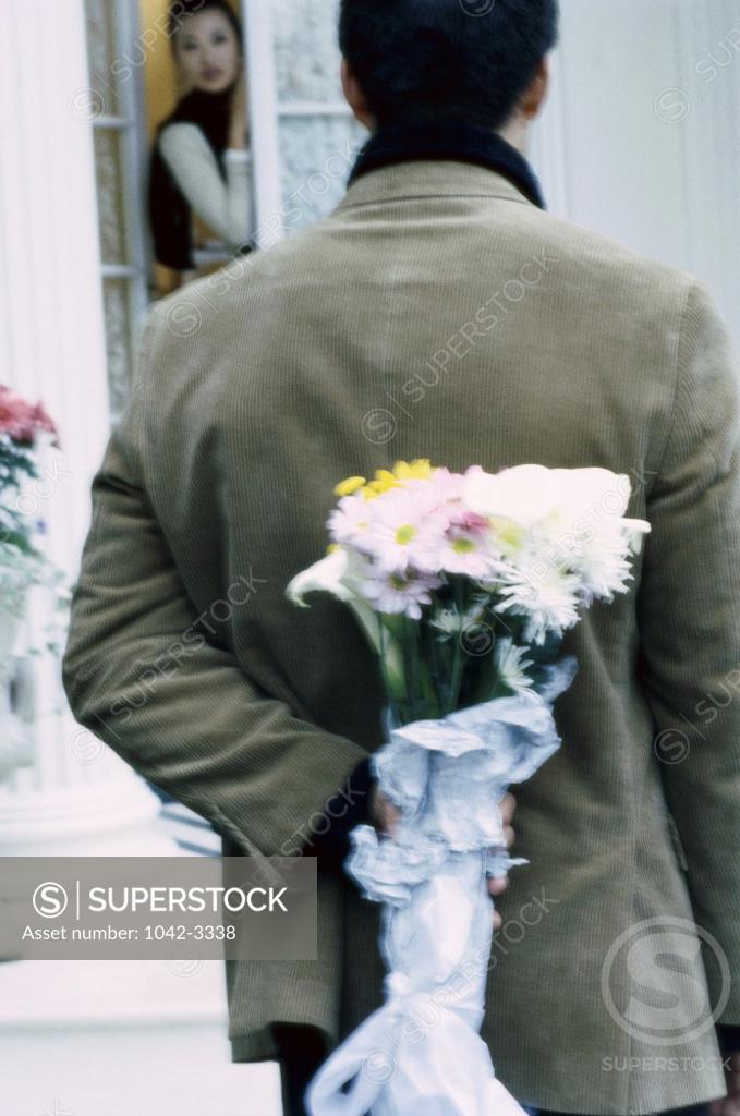 Stock Photo: 1042-3338 Rear view of a young man hiding a bouquet of flowers behind his back
