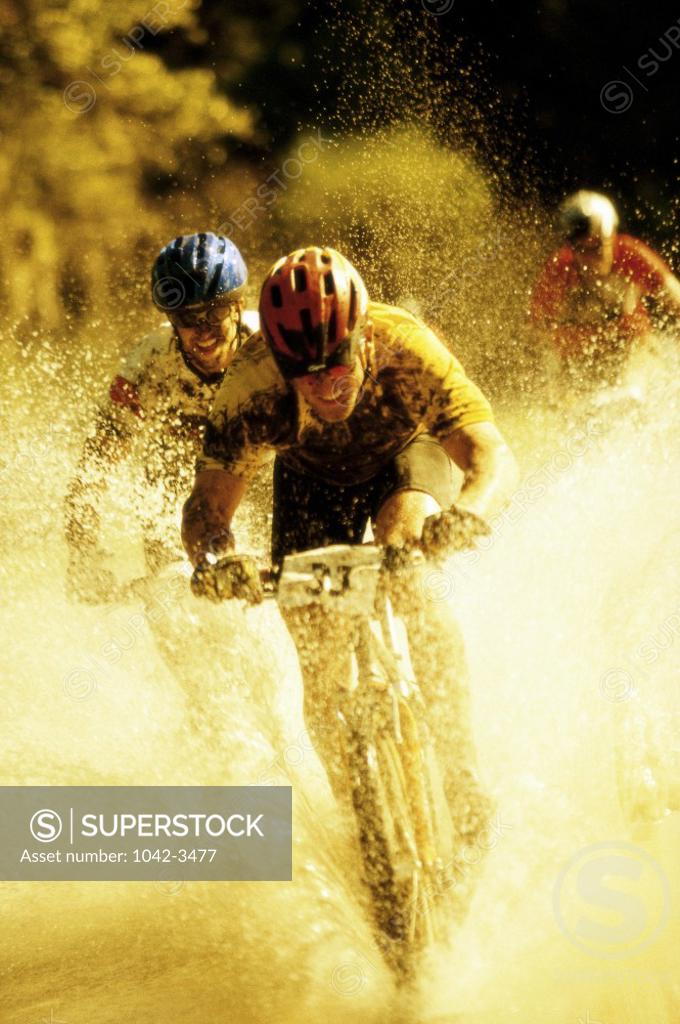 Stock Photo: 1042-3477 Young men riding bicycles through water