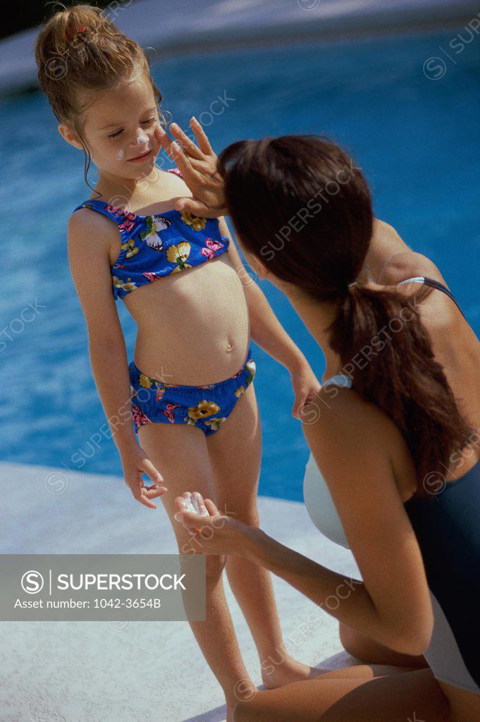 Stock Photo: 1042-3654B Rear view of a young woman applying sun block on her daughter