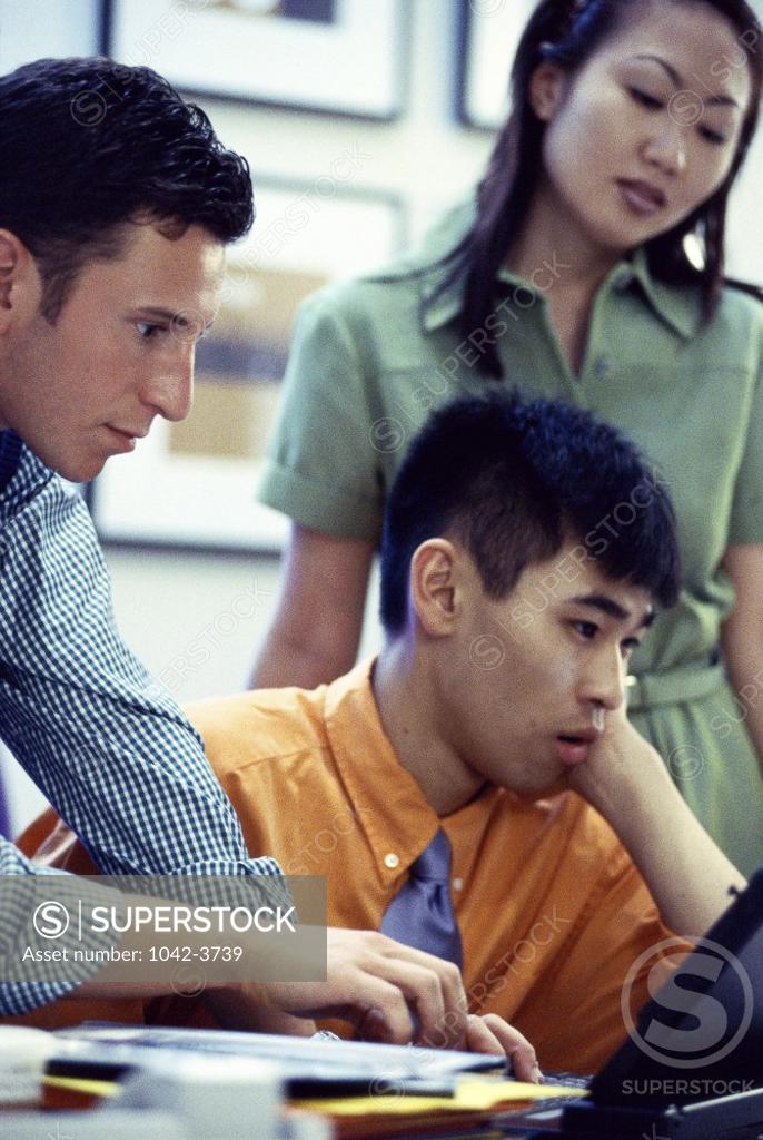 Stock Photo: 1042-3739 Two young men and a young woman in front of a computer monitor
