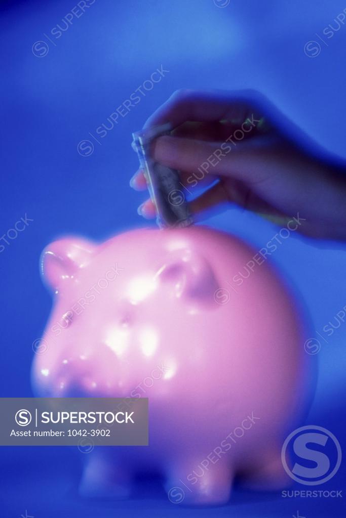 Stock Photo: 1042-3902 Person's hand dropping a dollar bill into a piggy bank
