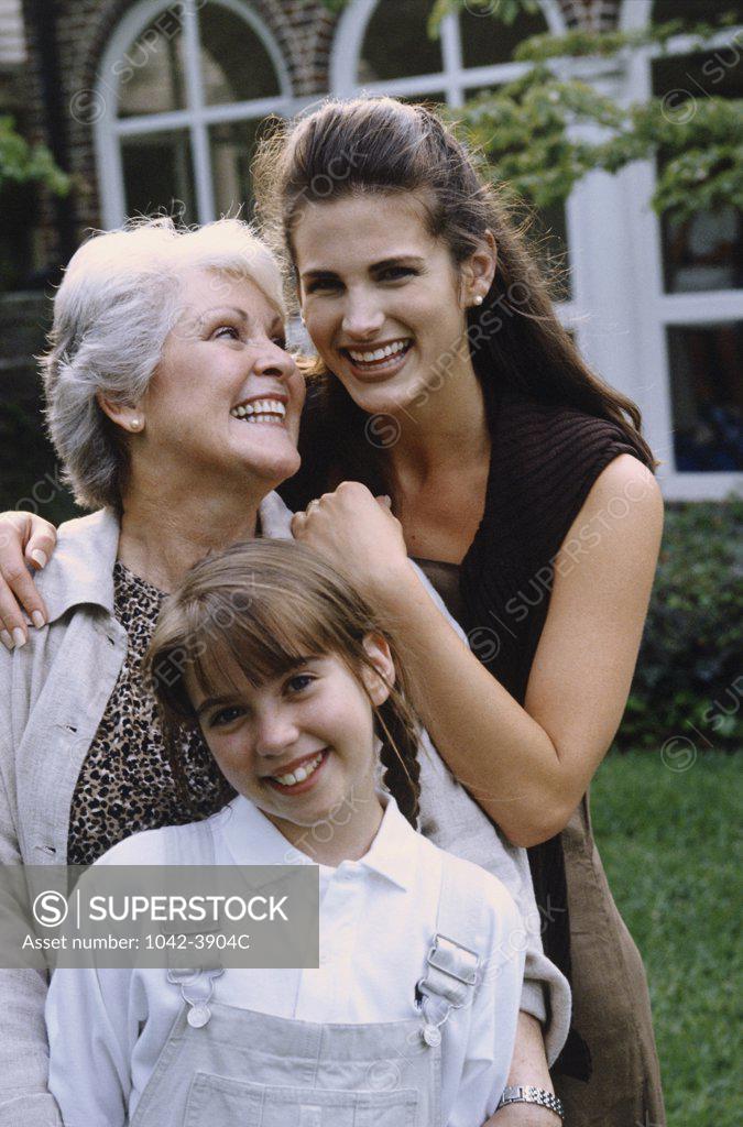 Stock Photo: 1042-3904C Portrait of a girl with her mother and grandmother standing on a lawn and smiling