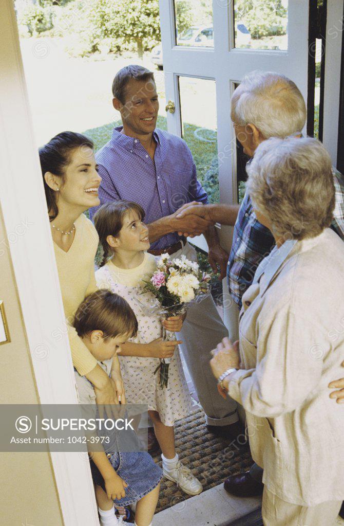 Stock Photo: 1042-3973 Grandparents greeting their children and grandchildren at the front door