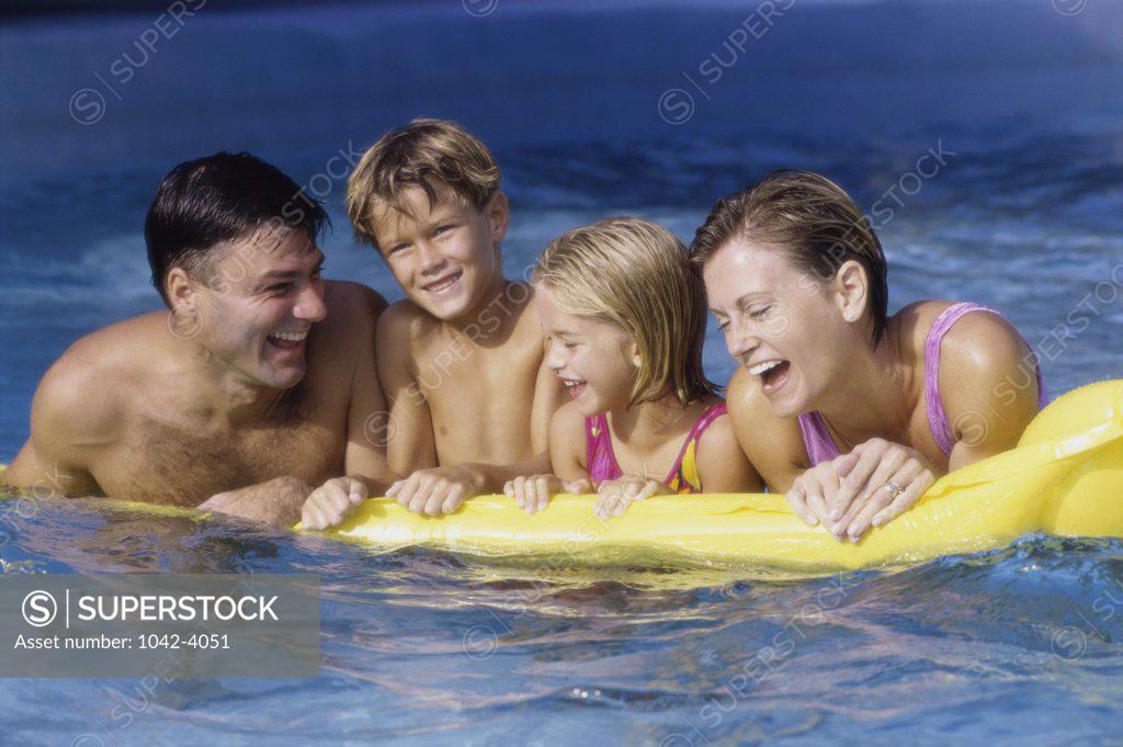 Stock Photo: 1042-4051 Young couple on a pool raft with their son and daughter