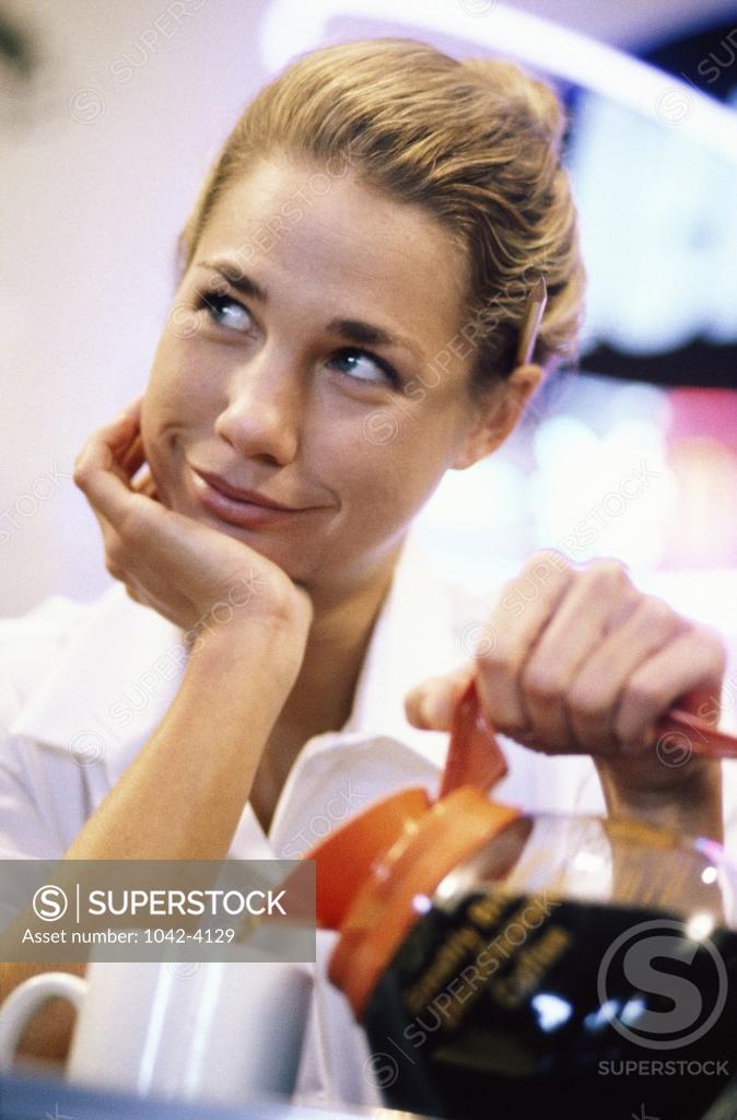 Stock Photo: 1042-4129 Young woman pouring coffee from a pot into a cup
