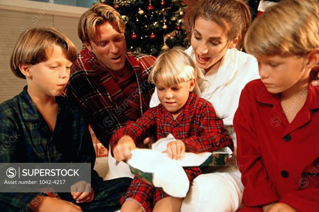Stock Photo: 1042-4217 Boy opening a Christmas present with his family