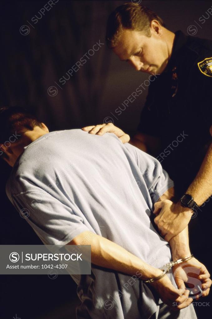 Stock Photo: 1042-4307 Side profile of a sheriff holding a young man in handcuffs