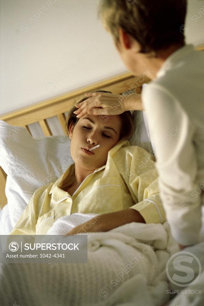 Stock Photo: 1042-4341 Rear view of a mother taking her daughter's temperature in bed
