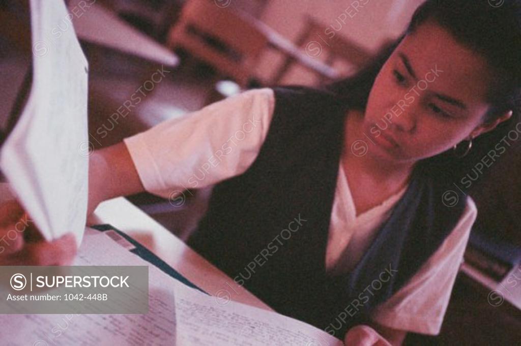 Stock Photo: 1042-448B Teenage girl holding a sheet of paper in a classroom