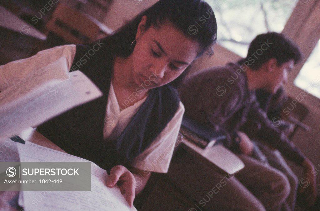 Stock Photo: 1042-449 Teenage girl holding sheets of papers in a classroom