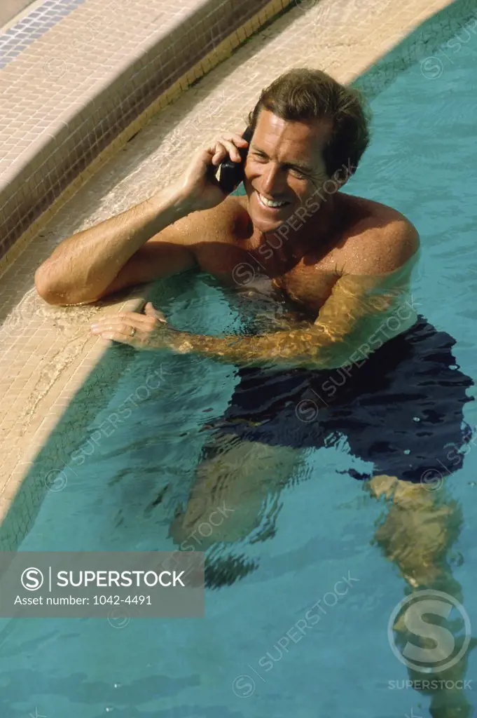 High angle view of a mid adult man talking on a mobile phone in a swimming pool