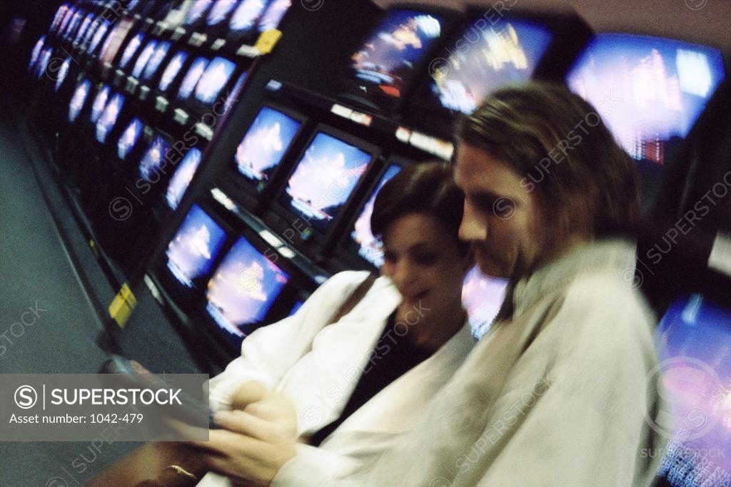 Stock Photo: 1042-479 Side profile of a young couple shopping for a television