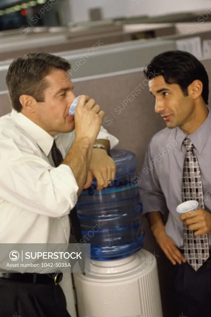 Two businessmen at a water dispenser in an office