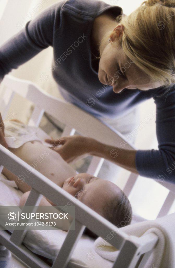 Stock Photo: 1042-5173 High angle view of a mother changing her baby boy's diaper