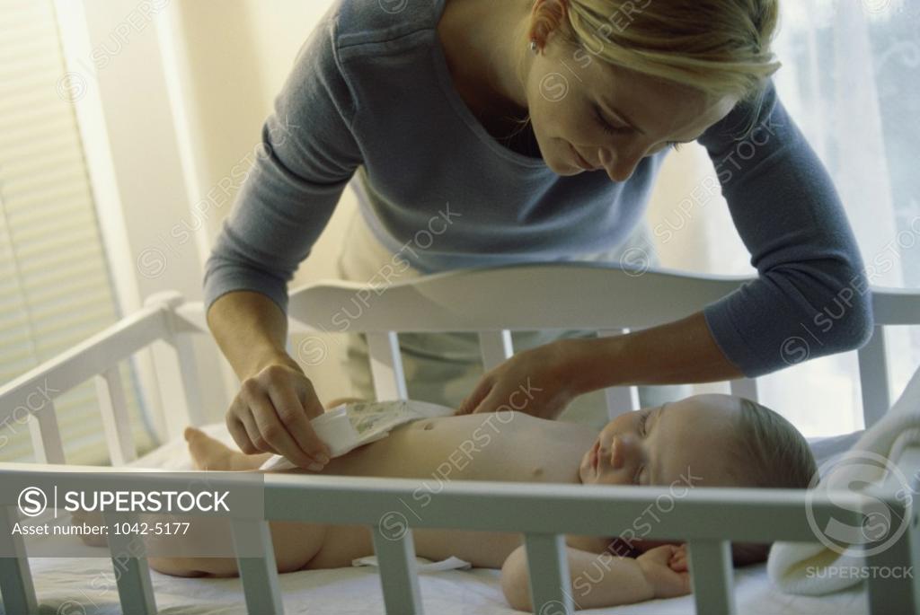 Stock Photo: 1042-5177 Mother changing diaper of a sleeping baby boy